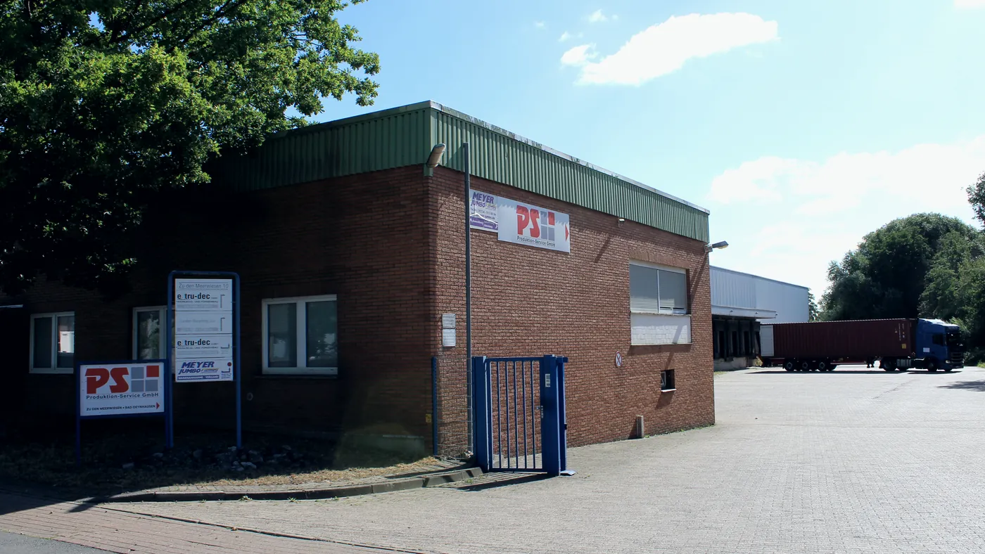 Backsteingebäude mit PS-Schild und Einfahrt, dahinter die Halle mit Sattelaufliegern, an der Betriebsstätte Zu den Meerwiesen 10 in Bad Oeynhausen