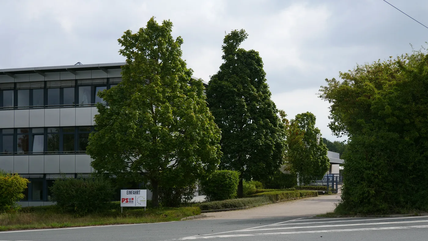 Verwaltungsgebäude mit Glasfassade und Schild „Einfahrt“ mit PS-Logo am Standort Südstraße 3 in Porta Westfalica