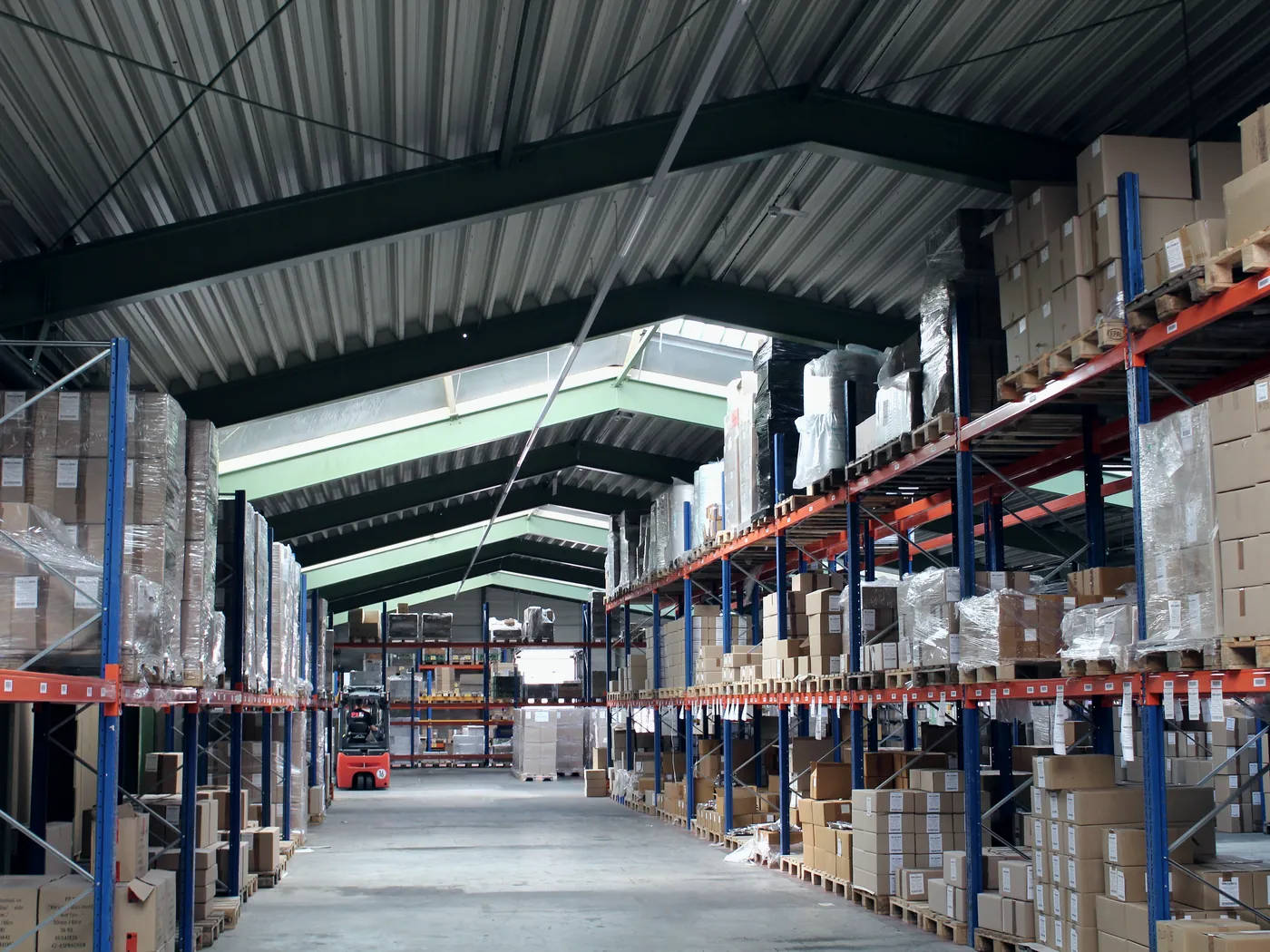 Blick durch die Lagerhalle der PS Produktion-Service GmbH mit beidseitigen Palettenregalen und Tageslicht
