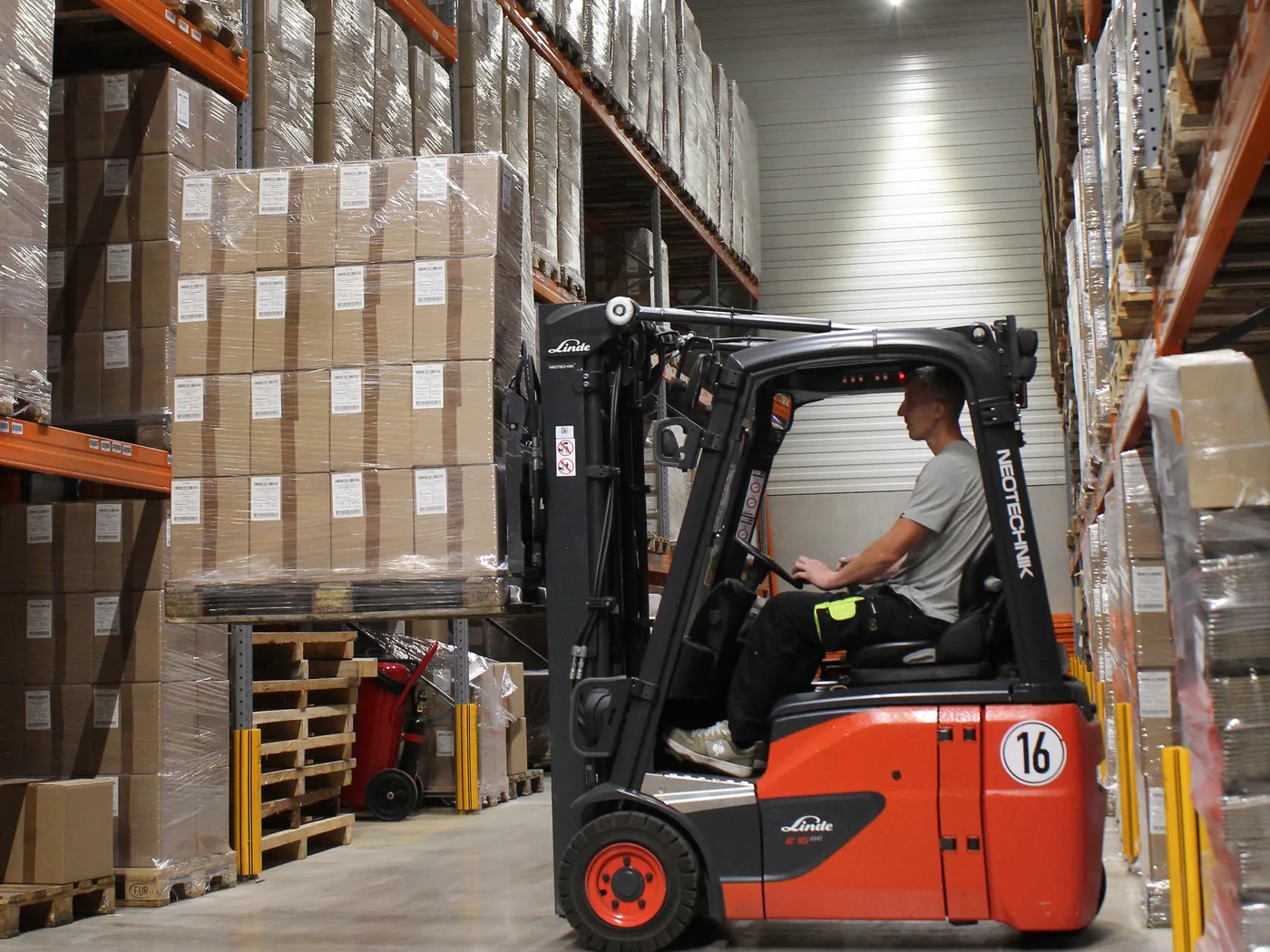 Forklift driver in the aisle between the high-bay racks of PS Produktion-Service GmbH