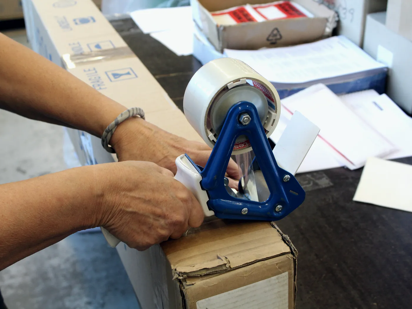 Parcel being sealed with a hand tape dispenser and prepared for handover to the carrier